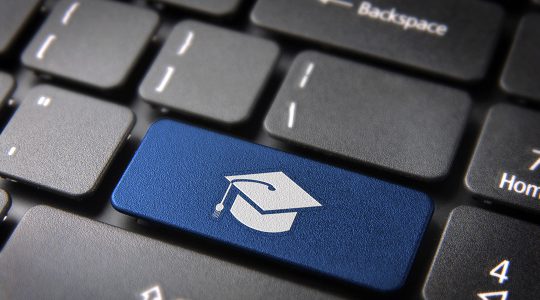 laptop keyboard with image of a graduation cap on a key